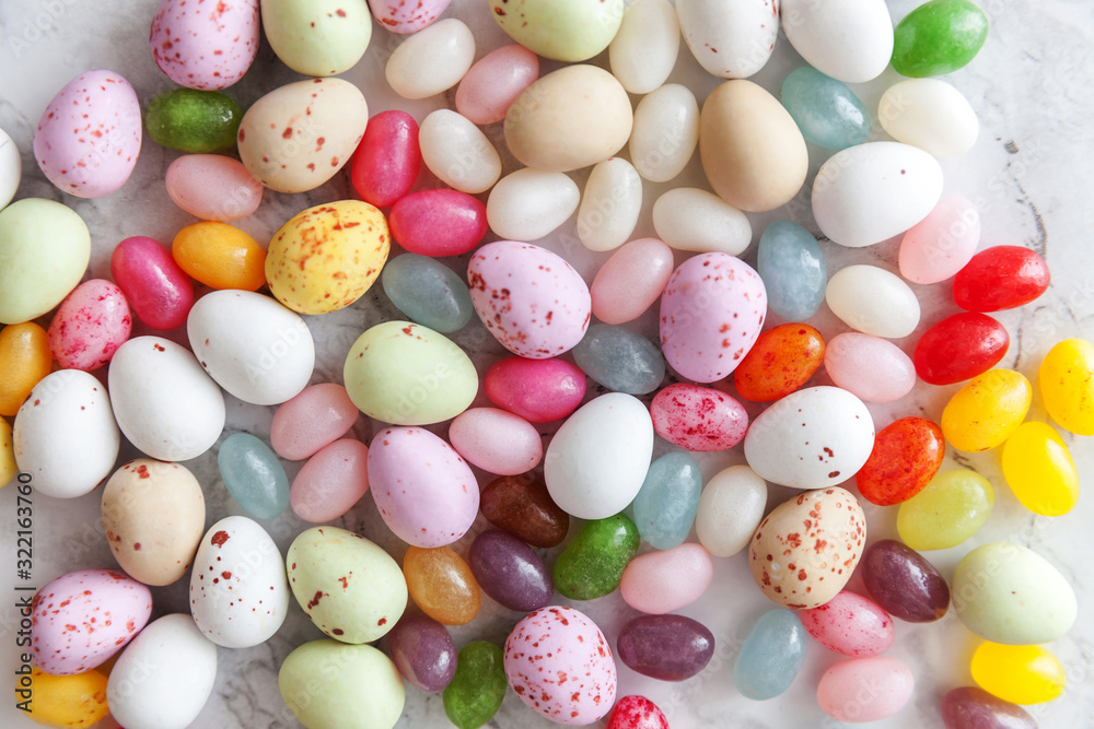 Happy Easter concept. Preparation for holiday. Easter candy chocolate eggs and jellybean sweets on trendy gray marble background. Simple minimalism flat lay top view copy space.