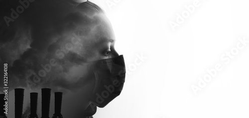 Double exposure of female face and factory chimneys polluting air. Portrait of young sad woman in protective respirator. Girl wearing medical mask. Free space for text. Black and white. photo