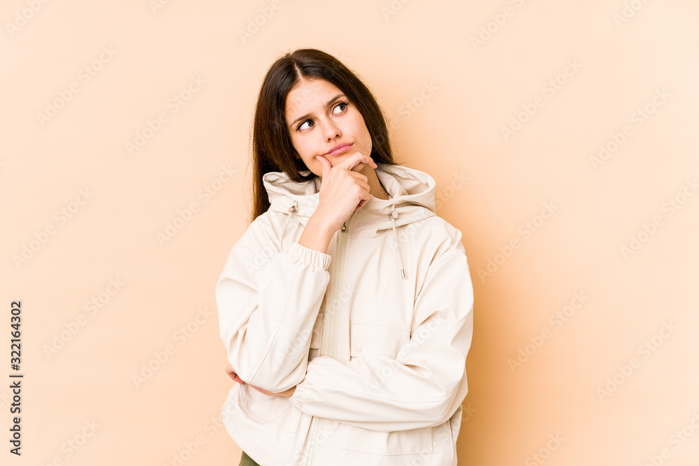 Young caucasian woman isolated on beige background thinking and looking up, being reflective, contemplating, having a fantasy. Young caucasian woman isolated on beige background thinking and looking up, being reflective, contemplating, having a fantasy.