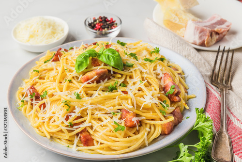 Classic homemade italian pasta carbonara with bacon, eggs, parmesan cheese and parsley in a plate with fork