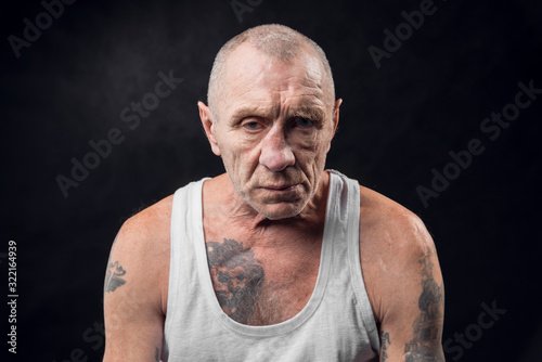 Portrait of an old alcoholic man on a black background