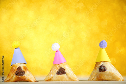 Purim holiday composition. Cookies with paper caps on blurred background