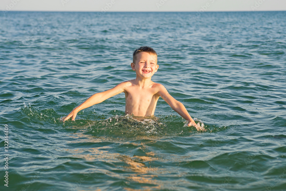 Happy child playing in the sea. Kid having fun outdoors. Summer vacation and healthy lifestyle concept