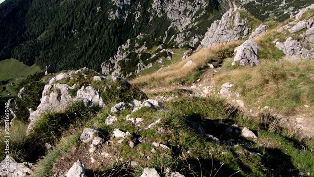 Forward dolly moving looking down over the edge of Alps Julian mountain summit covered with rocks and green grass Forward dolly moving looking down over the edge of Alps Julian mountain summit covered with rocks and green grass