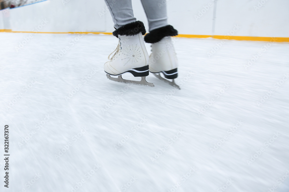 Fototapeta premium ice skating on the rink in motion close up. white figure skates on woman's legs