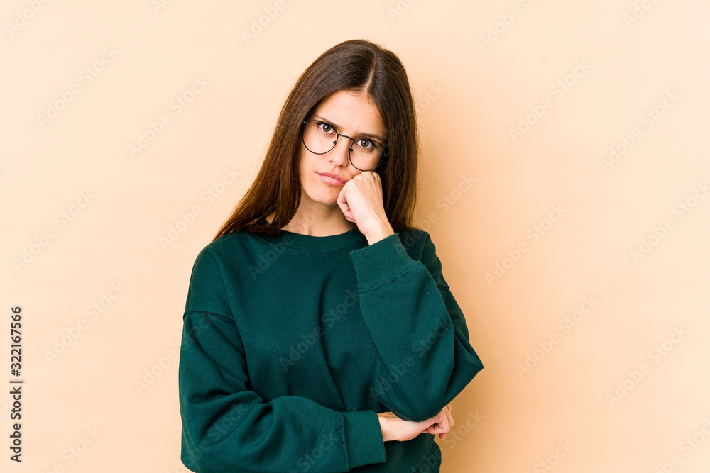 Young caucasian woman isolated on beige background who feels sad and pensive, looking at copy space.