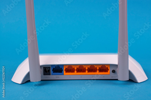 White wi-fi router on a blue background. Back view.