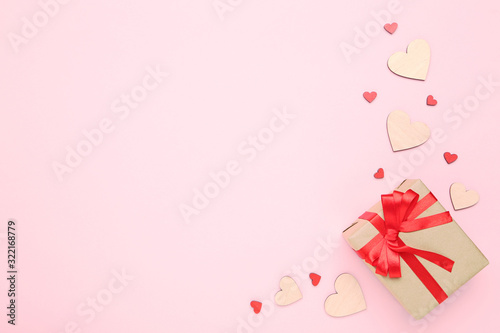 Gift box with ribbon and hearts on pink background
