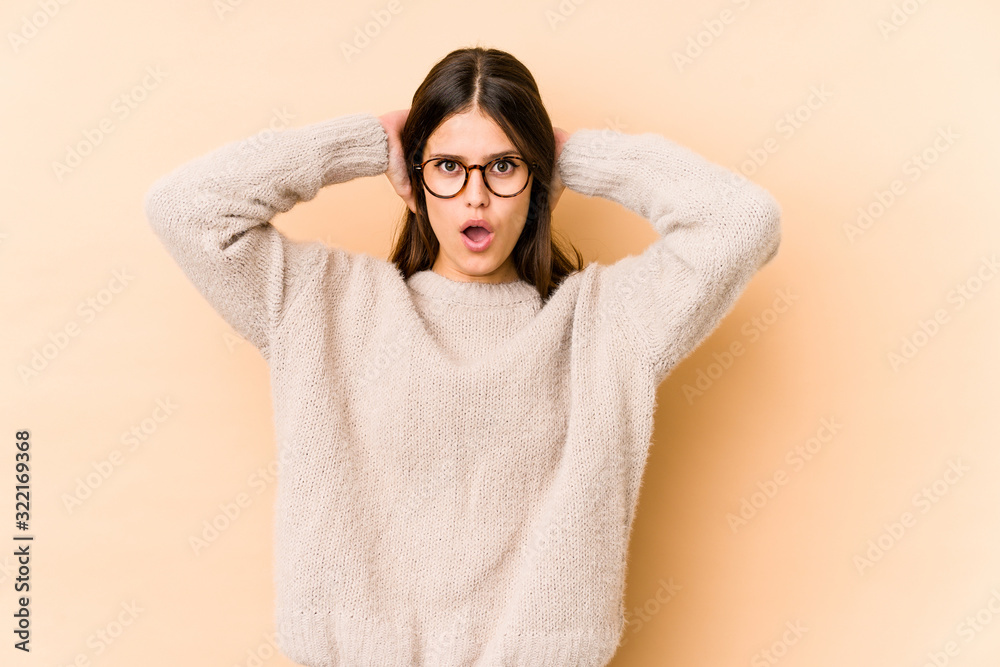 Young caucasian woman isolated on beige background screaming, very excited, passionate, satisfied with something. Young caucasian woman isolated on beige background screaming, very excited, passionate, satisfied with something.