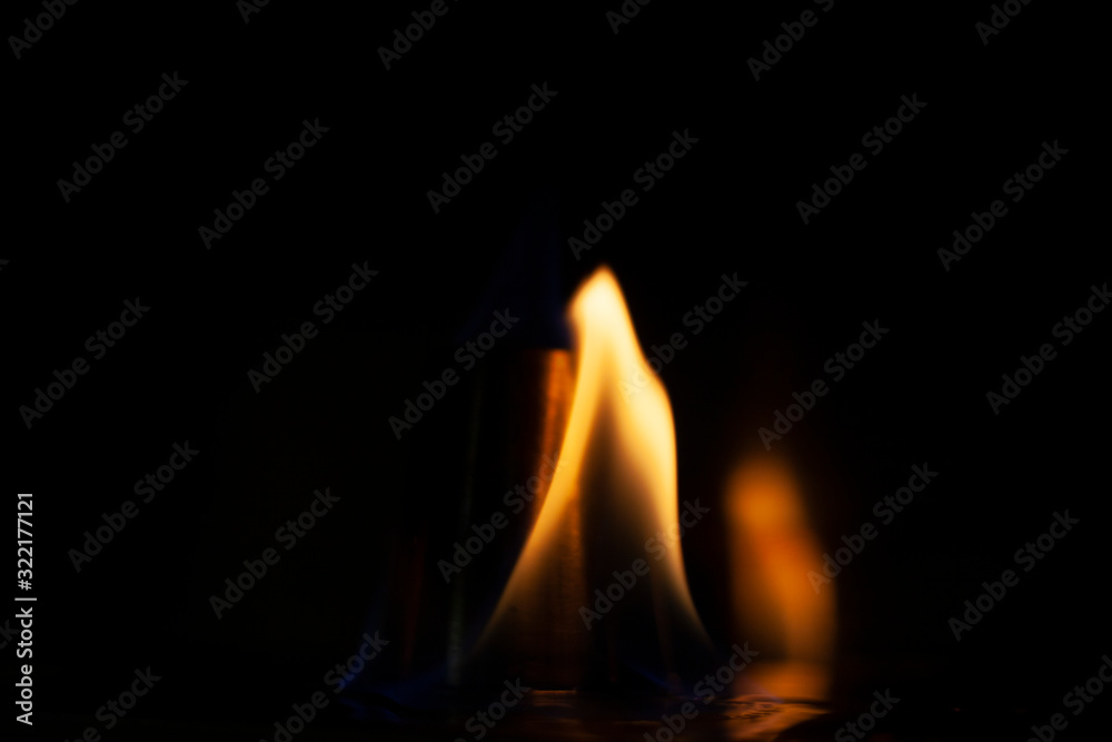 Alcohol burns on a stack for alcoholic drinks. Tongues of flame around a metal cup. Texture of fire. Yellow fire on a black background. Fire at the bar. The tradition of setting fire to alcohol. Alcohol burns on a stack for alcoholic drinks. Tongues of flame around a metal cup. Texture of fire. Yellow fire on a black background. Fire at the bar. The tradition of setting fire to alcohol.