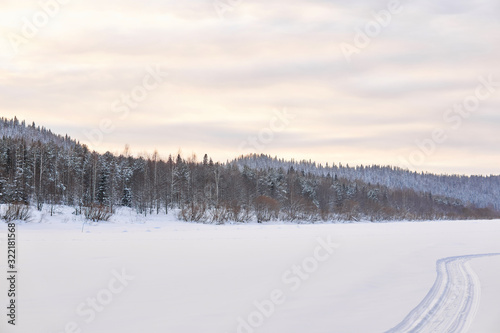 winter landscape with a wide frozen river in a snowy wooded valley
