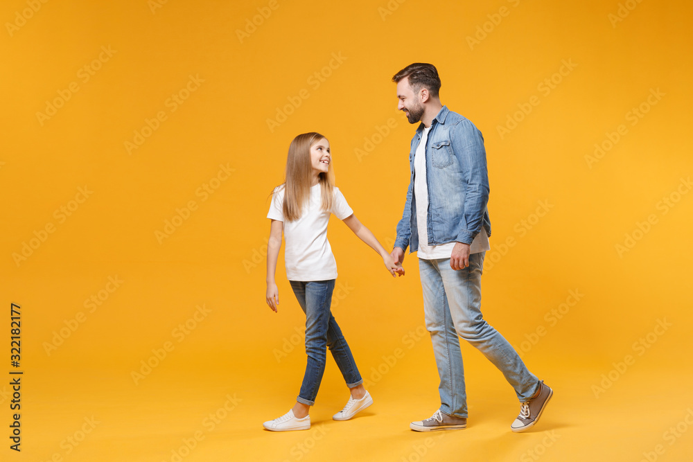 Side view of smiling bearded man have fun with child baby girl. Father little kid daughter isolated on yellow background. Love family parenthood childhood concept. Holding hands looking at each other. Side view of smiling bearded man have fun with child baby girl. Father little kid daughter isolated on yellow background. Love family parenthood childhood concept. Holding hands looking at each other.