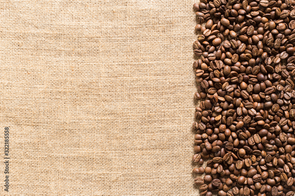 Fototapeta premium roasted coffee beans on sackcloth with space for text