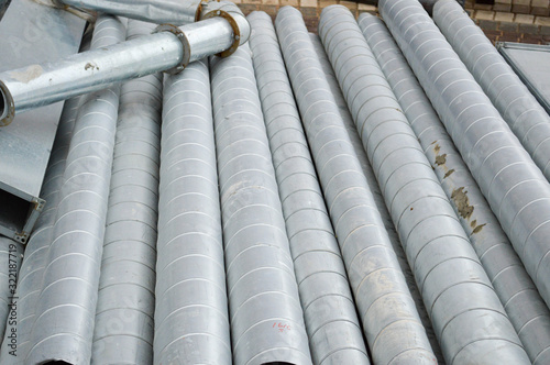 Large iron metal tin corrugated ventilation pipes of large diameter for the industrial construction of ventilation at a construction site during the repair