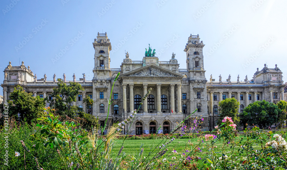 Budapest / Hungary - August 29 2019: Facade of the historic luxury building of the Ethnographic Museum in Budapest, Hungary. Ancient building with columns against the blue sky and green city park