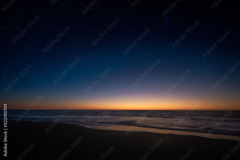 Fototapeta premium Amazing panoramic view of the Milky Way vanishing above the coast line of the Atlantic Ocean, as the sun rises over the horizon in the Southern hemisphere. Beautiful starry sunrise over the sea.