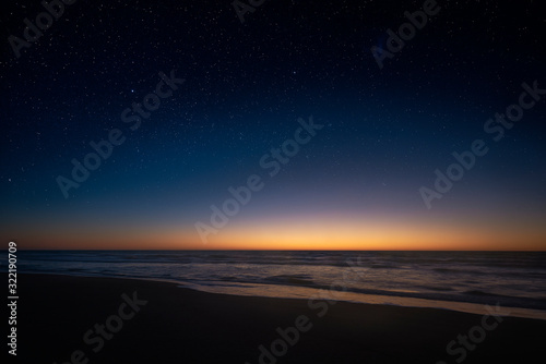 Amazing panoramic view of the Milky Way vanishing above the coast line of the Atlantic Ocean, as the sun rises over the horizon in the Southern hemisphere. Beautiful starry sunrise over the sea. © Galo Fernández