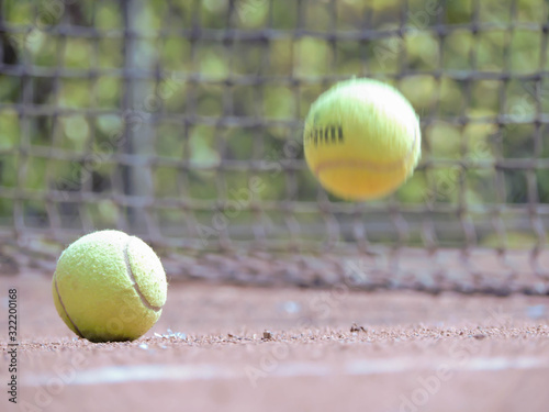 Pelota de tenis en movimiento con fondo natural acompañado con una raqueta en cancha de tenis