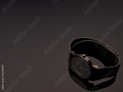 Black ladies luxury watch with metal strap mesh on a table gray gradient background