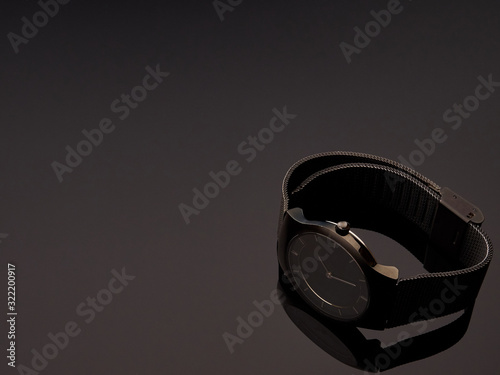 Black ladies luxury watch with metal strap mesh on a table gray gradient background photo