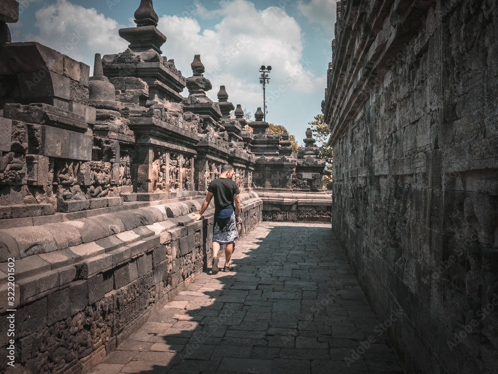 Young traveller walking in Borobudur Temple - the largest Buddhist temple in the world, Java, Indonesia, dedicated to the Trimurti