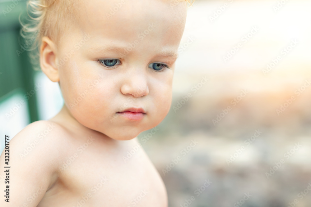 Close-up portrait of cute pensive upset caucasian 2 year old toddler boy portrait standing alone at beach summer day and looking aside. Child with far-away look. Kid thinking of life and future Close-up portrait of cute pensive upset caucasian 2 year old toddler boy portrait standing alone at beach summer day and looking aside. Child with far-away look. Kid thinking of life and future