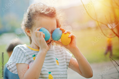 girl hid eyes behind found decorated eggs on Easter Day. holiday and child concept
