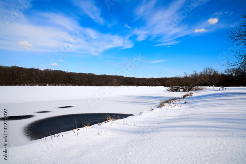Scenic View of Snow-Covered Lake, Blue Skies, White Clouds and Tree lined background  © Kenyatta Russell 
