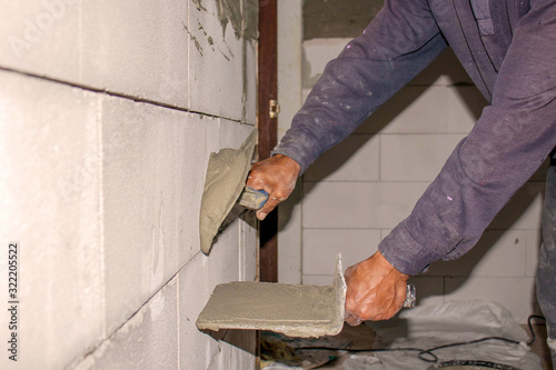 Close-up of a construction worker laying cement on the wall for building a house and building construction. © Arthon