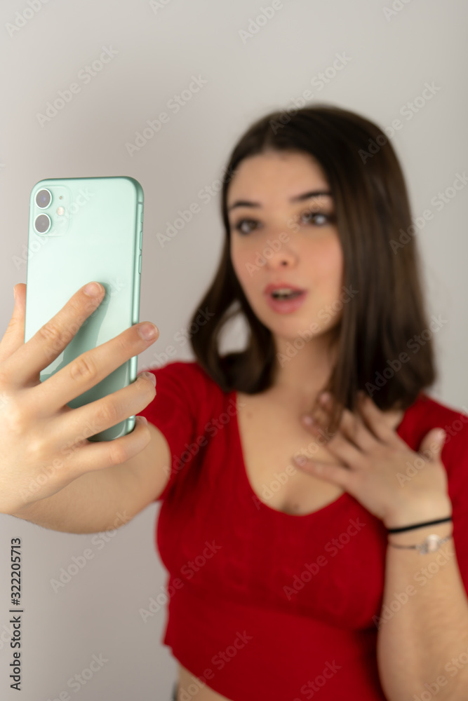 A young brunette girl with short hair and red shirt talking on video call with her cell phone A young brunette girl with short hair and red shirt talking on video call with her cell phone