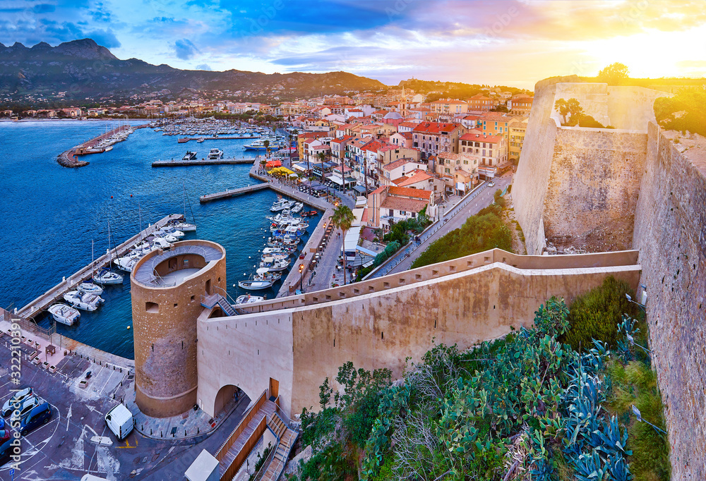 Φωτογραφία View from the walls of the citadel of Calvi on the old town with historic buildings at evening sunset