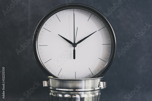 not wasting time, oversize clock with miniature garbage bin on business desk photo