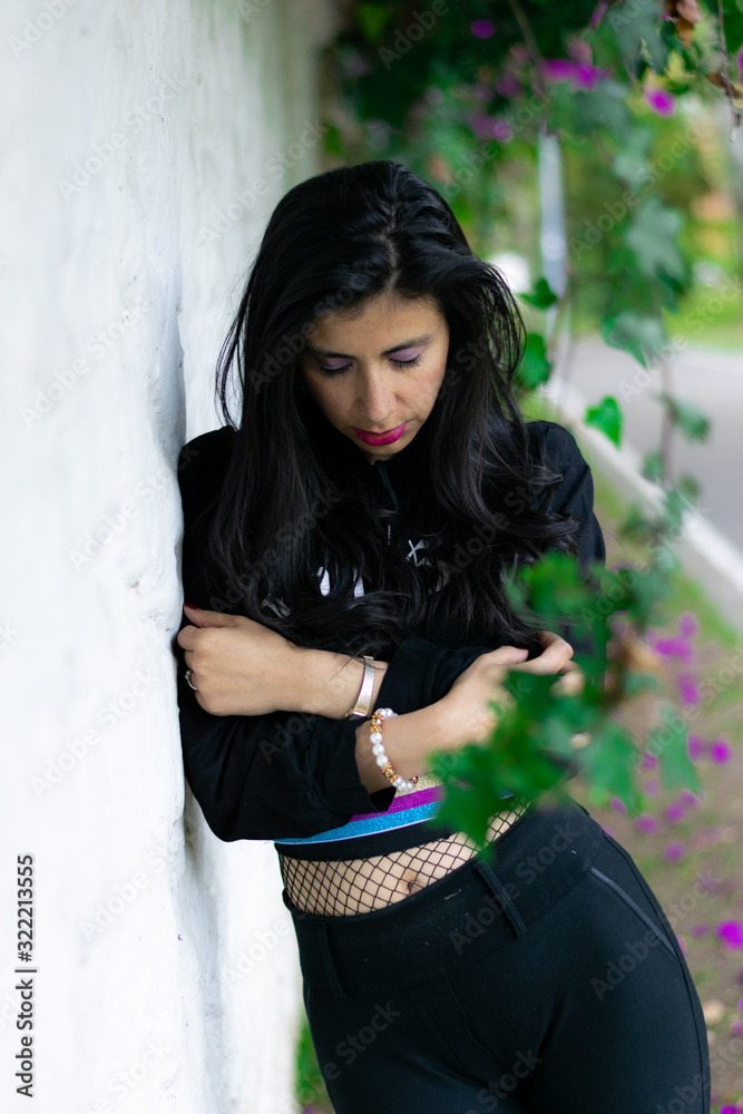 Fototapeta premium pretty Colombian woman lying on a white wall in a garden