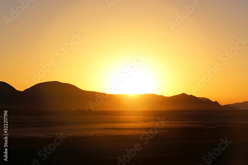 sunset against mountain in desert with camels