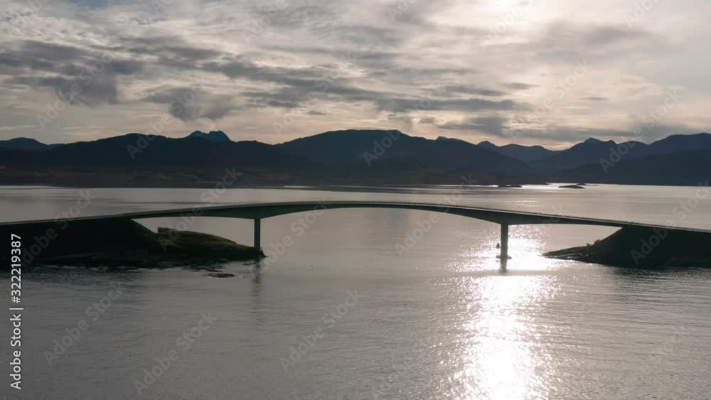 Bird's eye view of the famous Atlantic Road in Møre og Romsdal county, Norway. The silhouette of the bridge arcs above the sea, clouds on the horizon, the sea is calm and dark. Bird's eye view of the famous Atlantic Road in Møre og Romsdal county, Norway. The silhouette of the bridge arcs above the sea, clouds on the horizon, the sea is calm and dark.