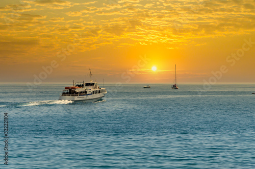 A white steamer sailing out to sea at sunset.