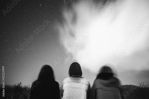 Low angle shot of three friends stargazing under cloudy skies