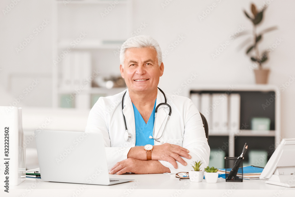 Male doctor sitting at table in clinic Male doctor sitting at table in clinic