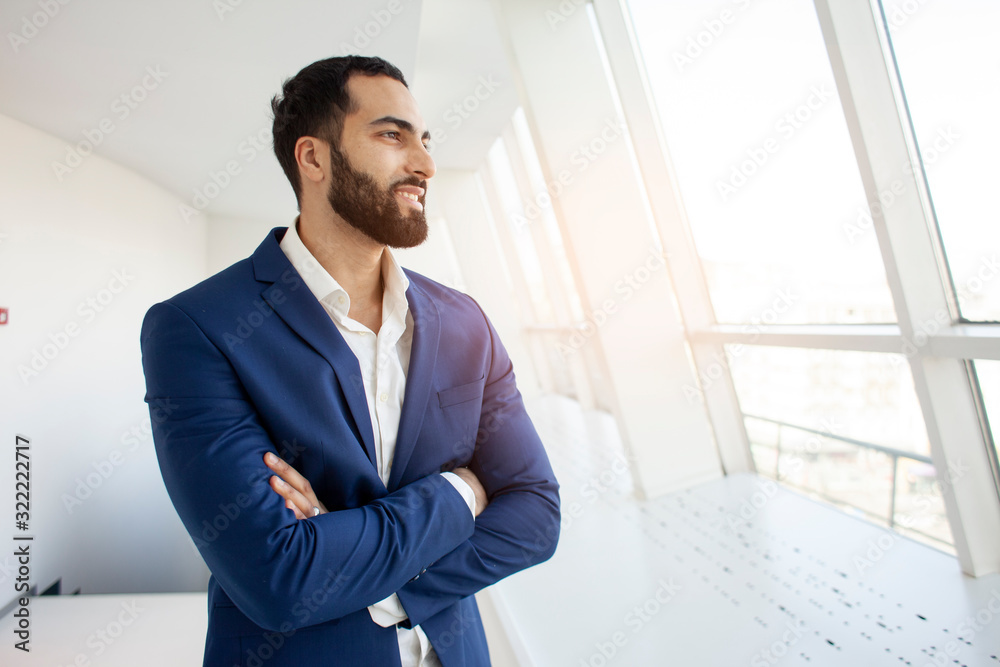 handsome successful company manager stands in a white office and looks out the window, portrait of a businessman at the workplace handsome successful company manager stands in a white office and looks out the window, portrait of a businessman at the workplace
