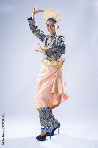 A beautiful Malaysian traditional female dancer performing a cultural dance routine in a traditional outfit on a stage. Full length portrait. photo