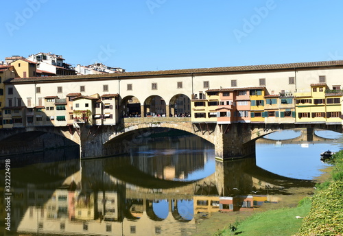 Ponte Vecchio and Arno River with blue sky and water reflections. Florence, Italy.