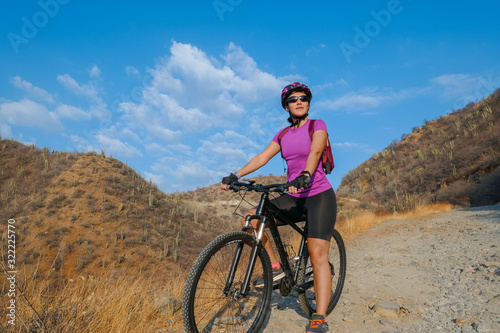 A young Latina woman with her bike in the mountains.