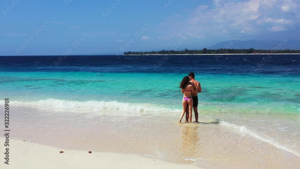 Young attractive couple in love standing on the sandy beach and hugging Young attractive couple in love standing on the sandy beach and hugging