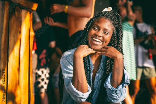 Charming beautiful young african american girl woman with black pigtails with piercings on her face sitting at a bar during a party