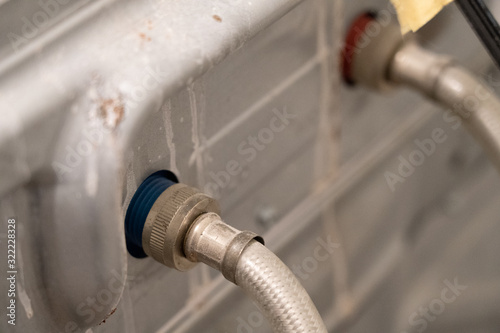 Water hoses attached to the back of a dirty washing machine photo