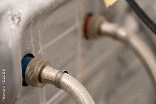 Water hoses attached to the back of a dirty washing machine