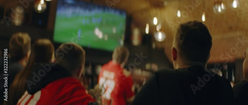 HANDHELD Model released, fans watching a game on a large TV in a sport pub. Shot on ARRI Alexa Mini with Atlas Orion 2x Anamorphic lens photo