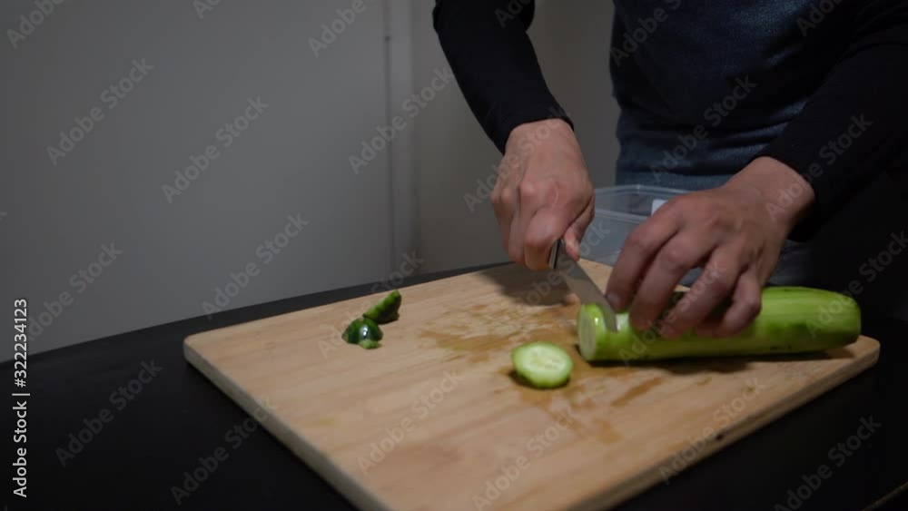 Chopping a cucumber on wooden chopping board Chopping a cucumber on wooden chopping board