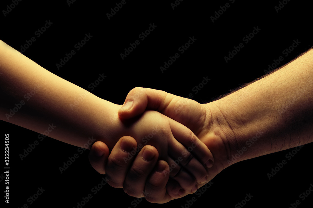 Handshake, father holds hand son. Father and Son Relationship Concept. Dark background. Place for text