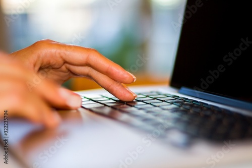 Woman types on a laptop keyboard at home, freelance concept, close up